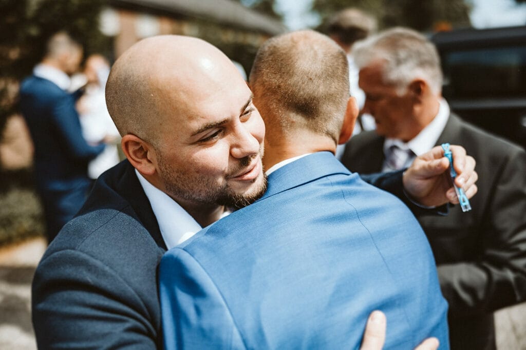 St. Marien Kirche Schloss Diersfordt Hochzeitsfotograf - Hochzeitsgast umarmt Bräutigam