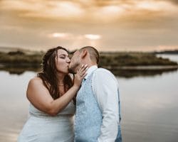 St. Marien Kirche Schloss Diersfordt Hochzeitsfotograf - Braut küsst Bräutigam vor Sonnenuntergang am See