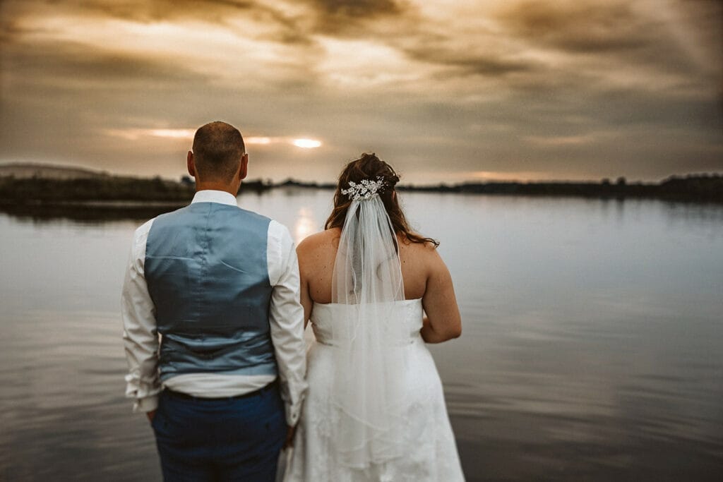 St. Marien Kirche Schloss Diersfordt Hochzeitsfotograf - Braut und Bräutigam blicken auf dem See