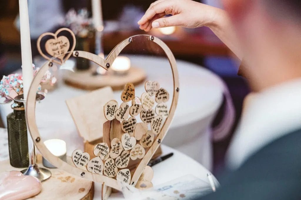 6 Alternativen zu einem traditionellen Hochzeits-Gästebuch - Hochzeitsgast wirft ein Herz aus Holz in einen Behälter