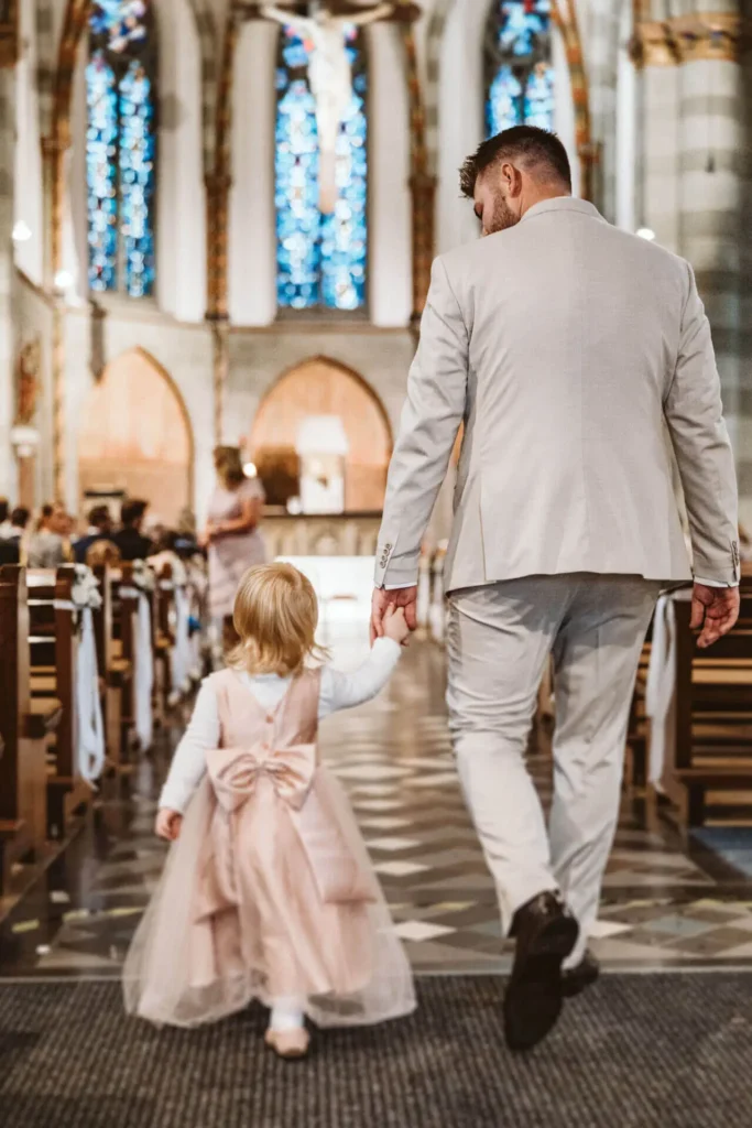 Blumenkinder und Blumenmädchen auf der Hochzeit - Tochter von Bräutigam läuft Hand in Hand mit ihm zum Altar in der Kirche