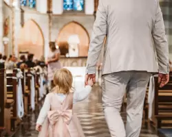 Blumenkinder und Blumenmädchen auf der Hochzeit - Tochter von Bräutigam läuft Hand in Hand mit ihm zum Altar in der Kirche