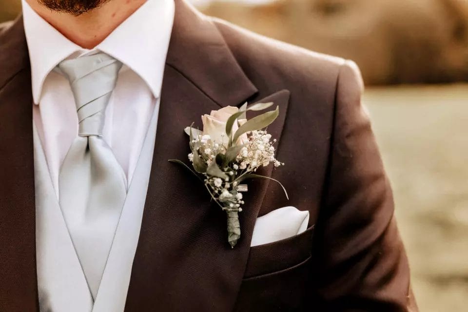 Der Braustrauß - welche Blumen gehören zur Hochzeit - Bräutigam mit Ansteckblumen im schwarzen Anzug
