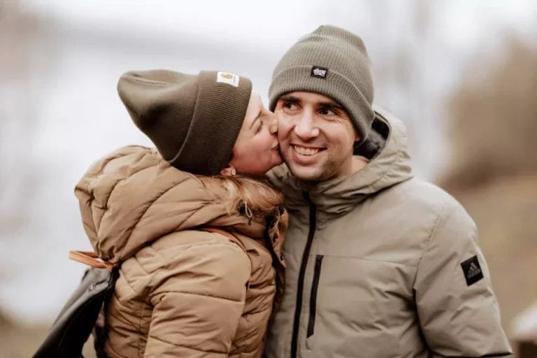 Engagement Session - Paar küsst sich mit Mützen zur herbstlichen Jahreszeit