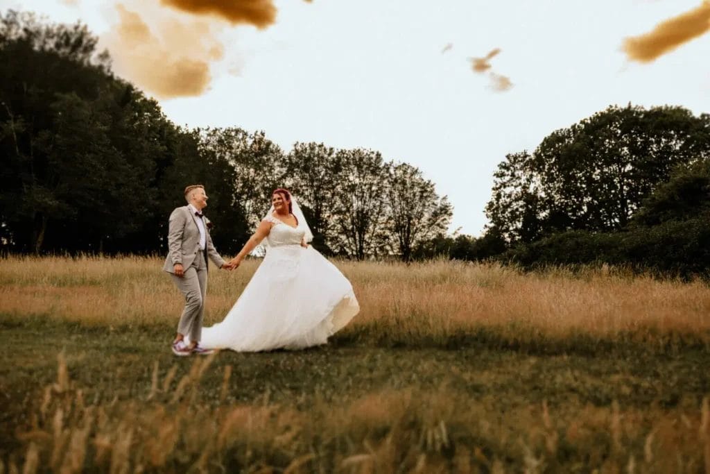 Freie Trauung, kirchliche Trauung und Standesamt - Heiraten mit Vorteilen und Nachteilen - Hochzeitspaar läuft zum Sonnenuntergang Feld entlang