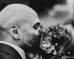Regen am Hochzeitstag - Bräutigam küsst Braut auf den Kopf und schließt seine Augen dabei