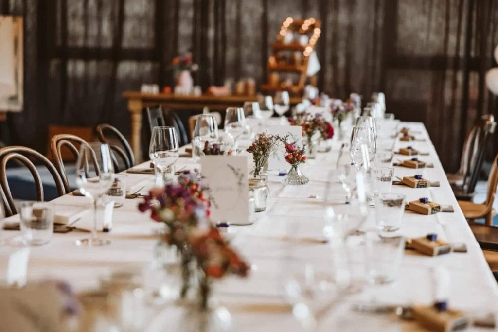 Tischdeko zur Hochzeit - Lange Tafel mit Blüten und kleinen Gastgeschenken in Form von Süßigkeiten