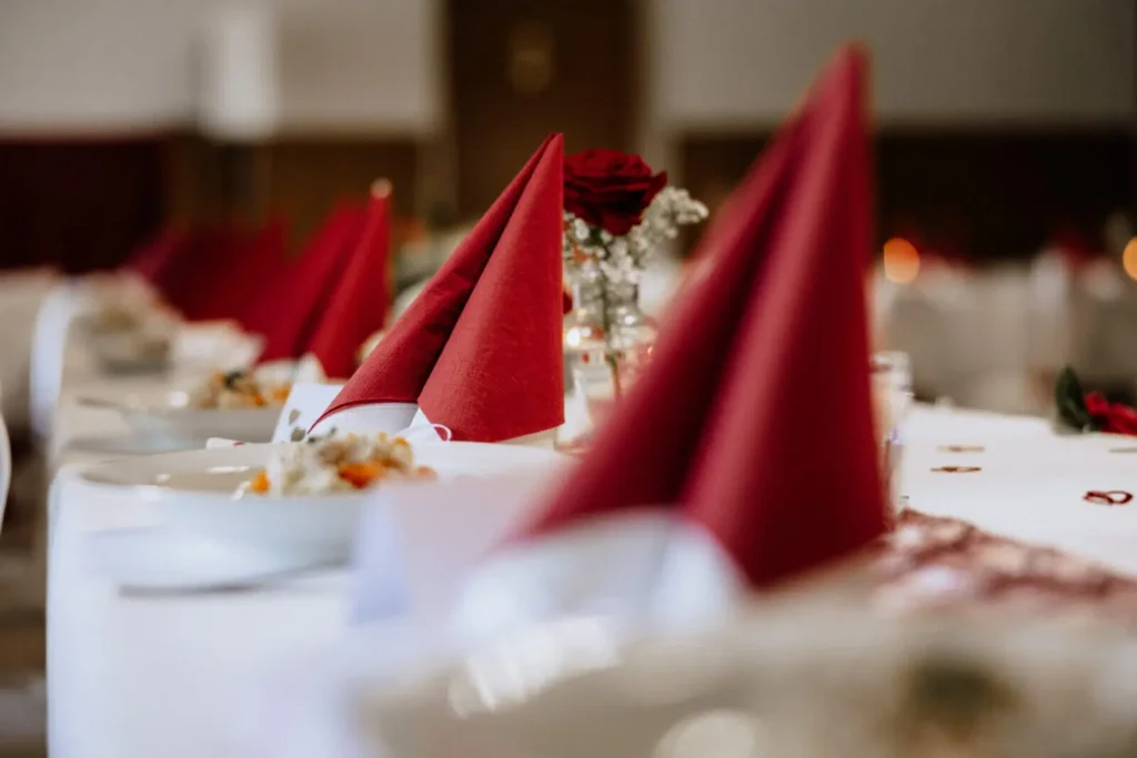 Tischdeko zur Hochzeit - Rote Servietten stehen auf einem langen Tisch