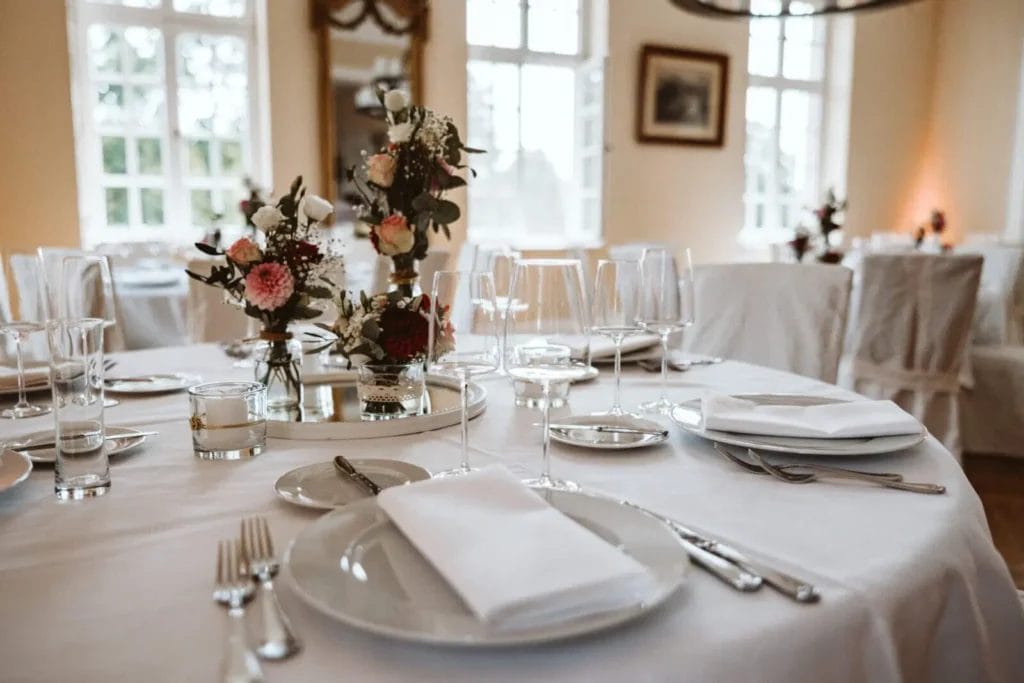 Tischdeko zur Hochzeit - Runder, eingedeckter Tisch mit Blumen und Vasen