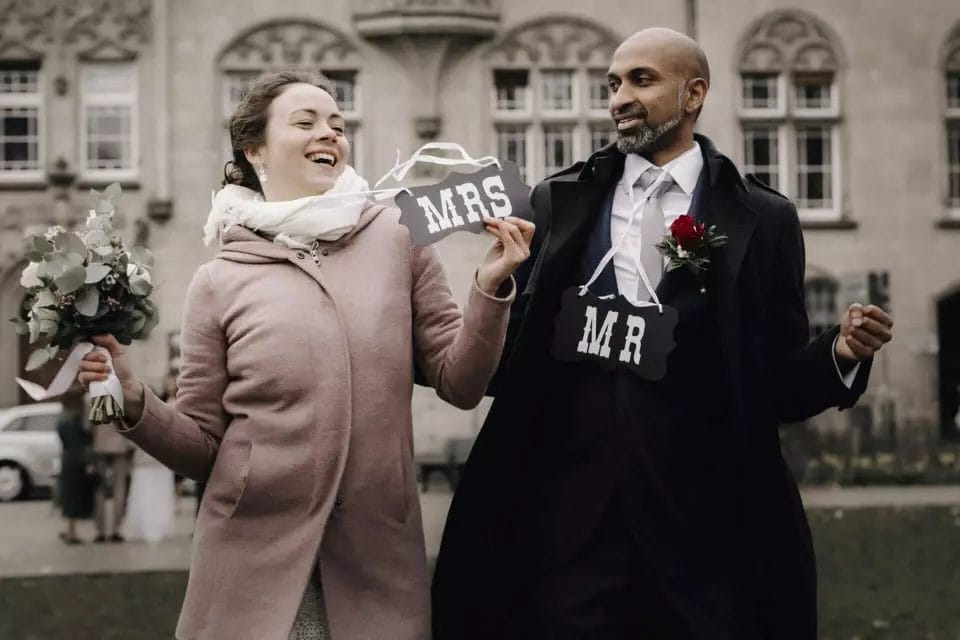 Was kostet ein guter Hochzeitsfotograf - Brautpaar hält Mrs und Mr Schild in die Luft und feiert ihre Liebe