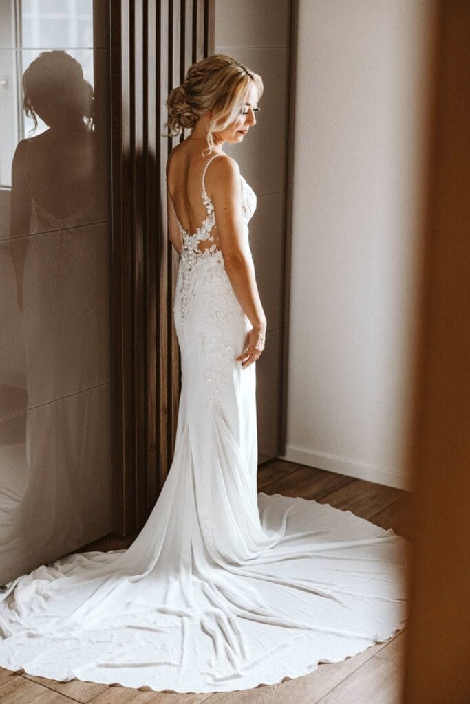 Hochzeitsfotograf Remscheid Hochzeit Heiraten Hochzeitsfotos - Braut steht vor Kleiderschrank. Brautkleid ist aufgefaltet