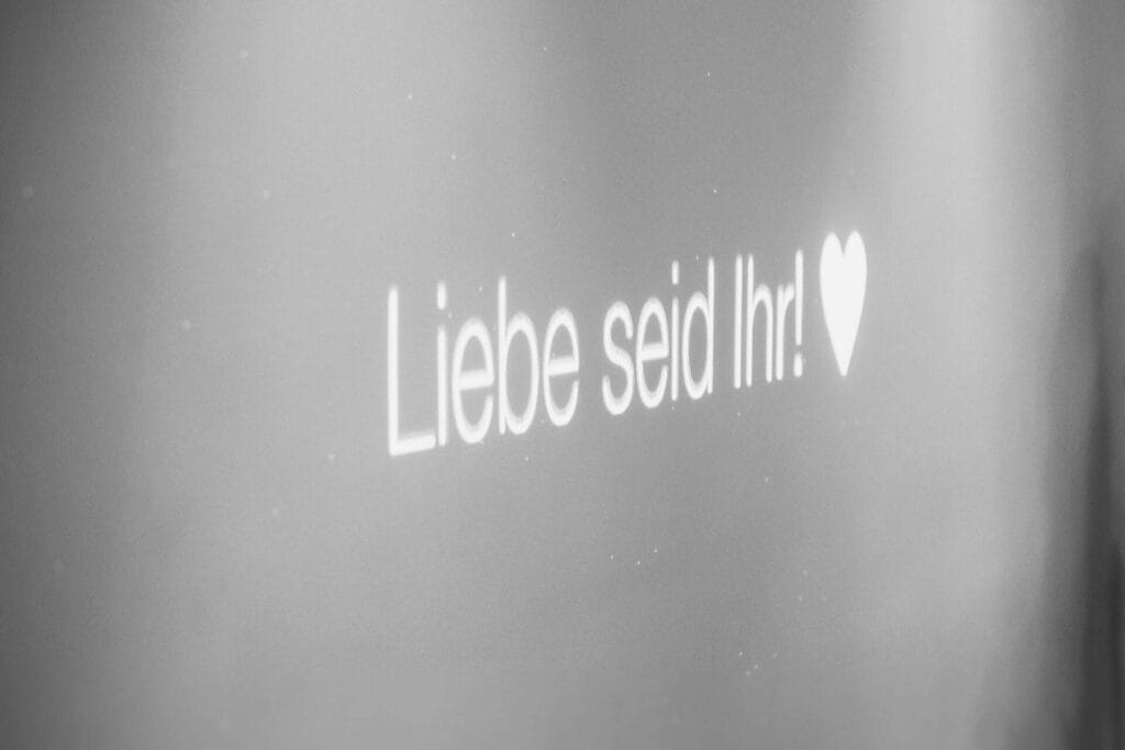 Hochzeitsfotograf Bochum Hochzeit Heiraten Hochzeitsfotos - Mit dem Beamer ist auf der Hochzeitsparty die Schrift "Liebe seid Ihr!" und einem Herzchen-Icon zu sehen