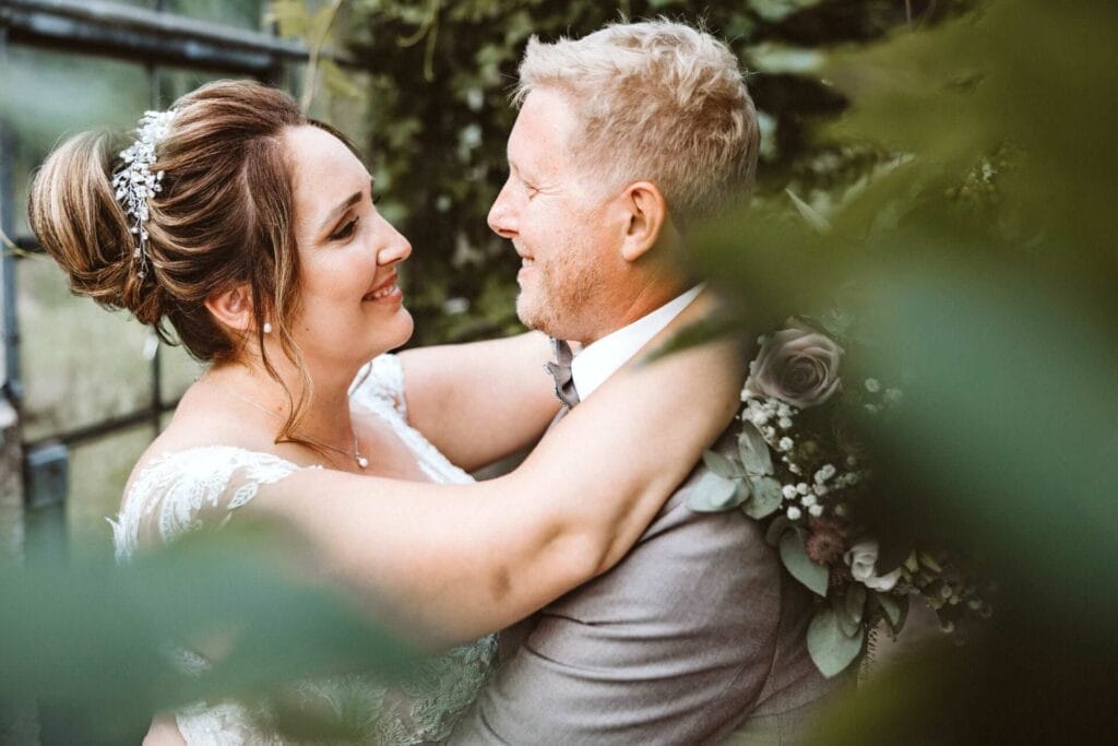 Hochzeitsfotograf Duisburg Hochzeit Heiraten Hochzeitsfotos - Die Braut schaut bei der Brautpaar-Session ihren Bräutigam in die Augen und umarmt ihn. Das Hochzeitspaar sieht glücklich aus. Beide lächeln sich an