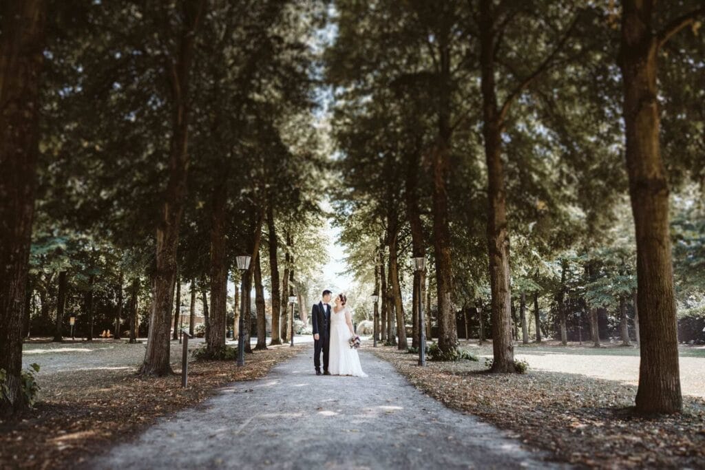 Hochzeitsfotograf Duisburg Hochzeit Heiraten Hochzeitsfotos - Das Brautpaar steht bei der Brautpaar-Session zueinander auf einer Straße. Um sie herum sind Bäume. Es ist eine Baum-Allee