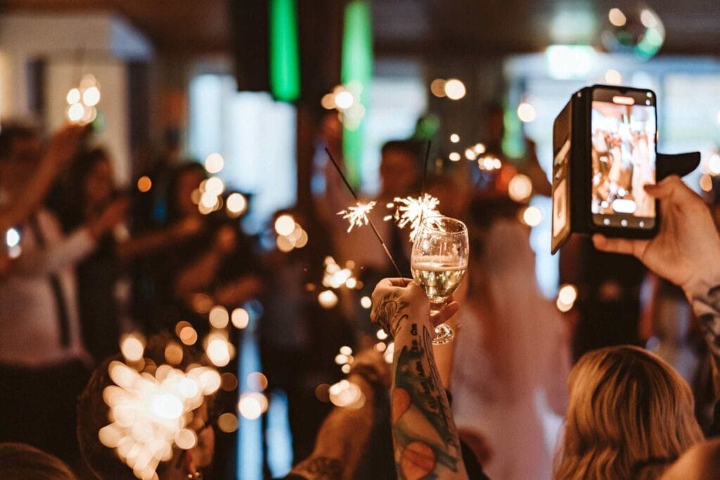 Hochzeitsfotograf Duisburg Hochzeit Heiraten Hochzeitsfotos - Sternspeier, Wunderkerzen und ein Sektglas sowie ein Smartphone werden von den Händen der Hochzeitsgäste zur Party in die Höhe gehalten. Das Brautpaar wird für den Hochzeitstanz gefeiert