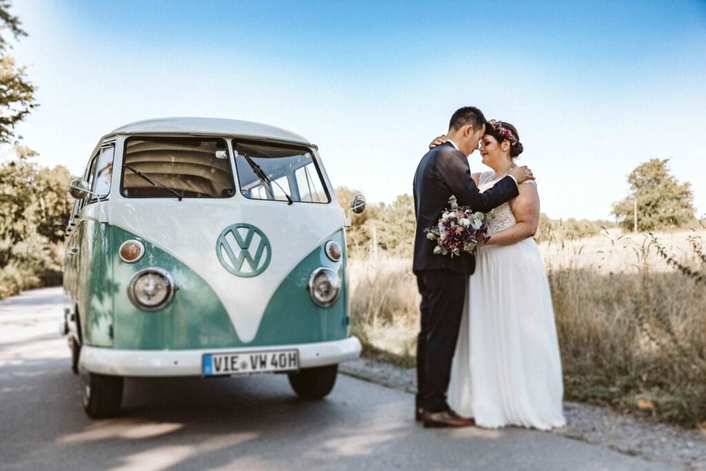 Hochzeitsfotograf Oberhausen Hochzeit Heiraten Hochzeitsfotos - Braut und Bräutigam umarmen sich und legen ihre Stirn aufeinander. Sie stehen auf einer Straße. Links von Ihnen steht ein VW Bulli in weißer und türkiser Farbe