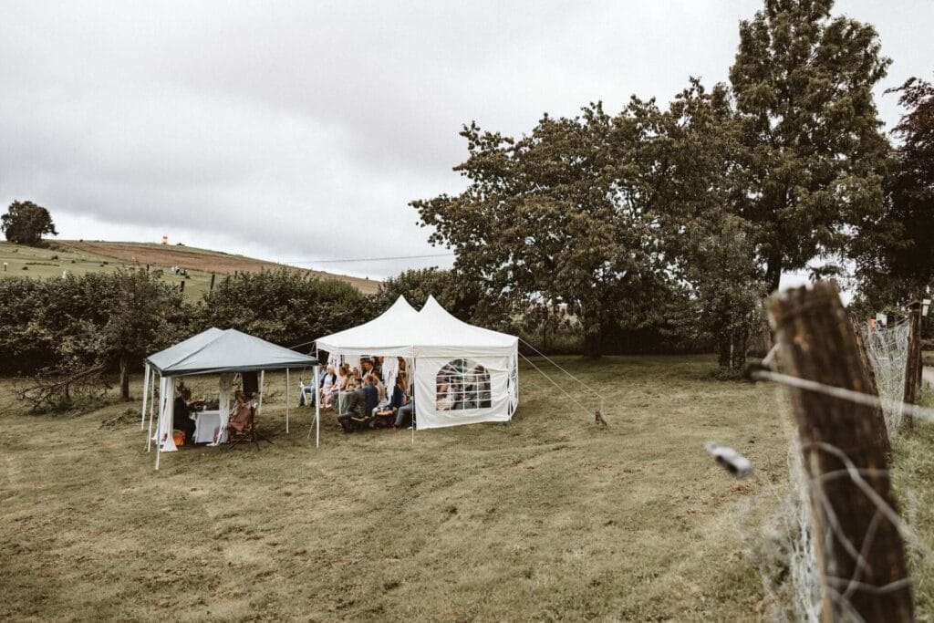 Hochzeitsfotograf Herne Hochzeit Heiraten Hochzeitsfotos - Pavillons aufgestellt für die freie Trauung für die freie Hochzeit des Brautpaars auf einer Wiese. Im Hintergrund sind Bäume und Felder zu sehen. Im Vordergrund ein Zaun