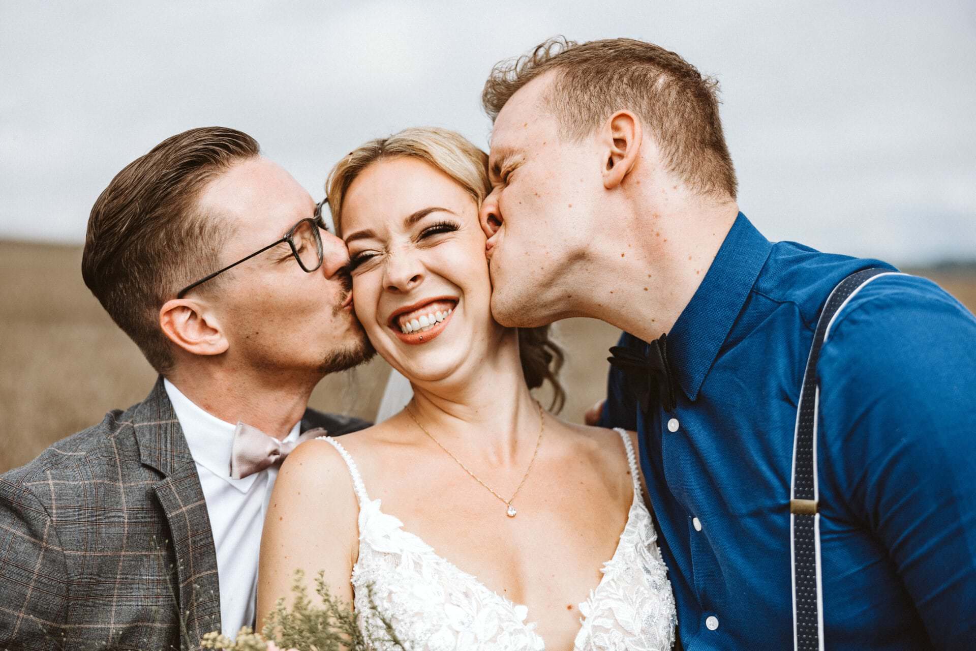 Hochzeitsfotograf Wesel Hochzeit Heiraten Hochzeitsfotos - Braut wird von Trauzeuge und Bräutigam auf die Wange geküsst. Die Braut lächelt