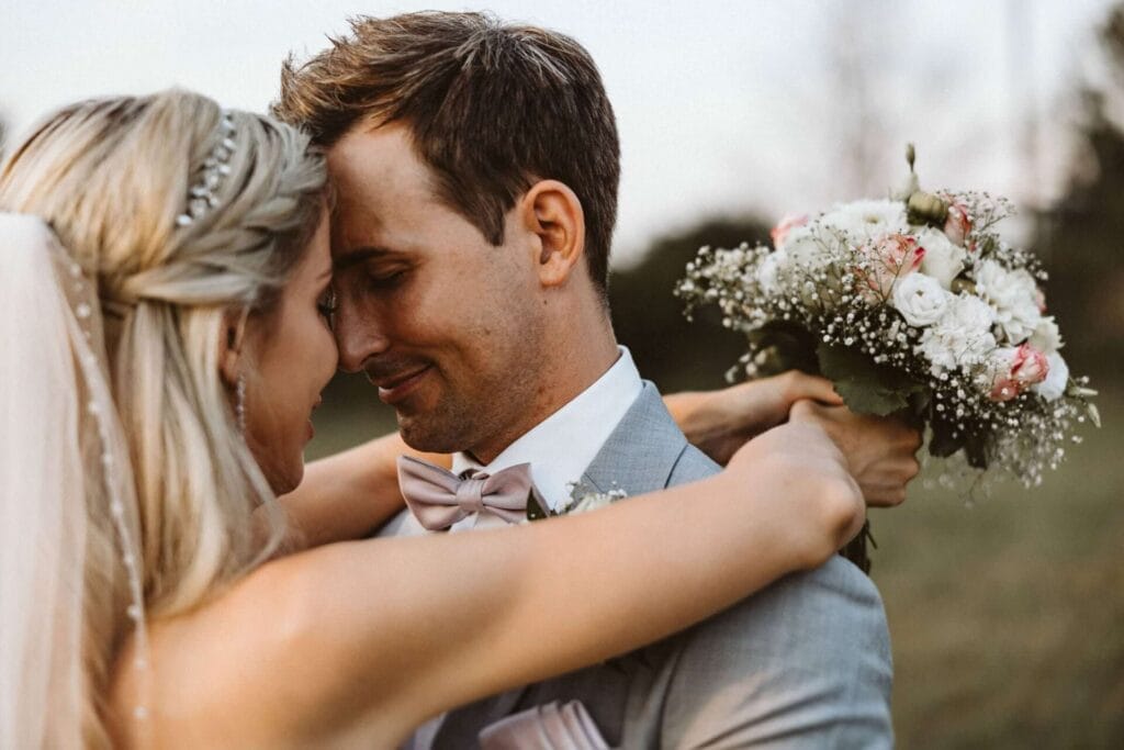 Hochzeitsfotograf Schwerte Hochzeit Heiraten Hochzeitsfotos - Braut und Bräutigam stehen vor einem alten Schulbus, der die Türen offenstehen hat. Sie schauen in verschiedenen Richtungen. Der Bus steht in dem Tierpark beziehungsweise dem Zoo ZOOM Erlebniswelt