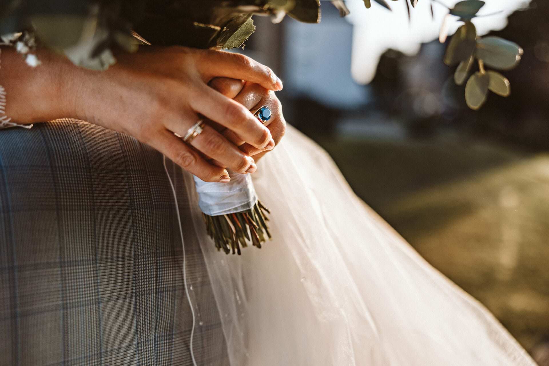 Hochzeitsfotograf Krefeld Hochzeit Heiraten Hochzeitsfotos - Ein blauer Ring und der Hochzeitsring bei der Braut sind zu erkennen, während sie den Bräutigam umarmt. Sie hält den Blumenstrauß fest. Es ist eine Detailaufnahme