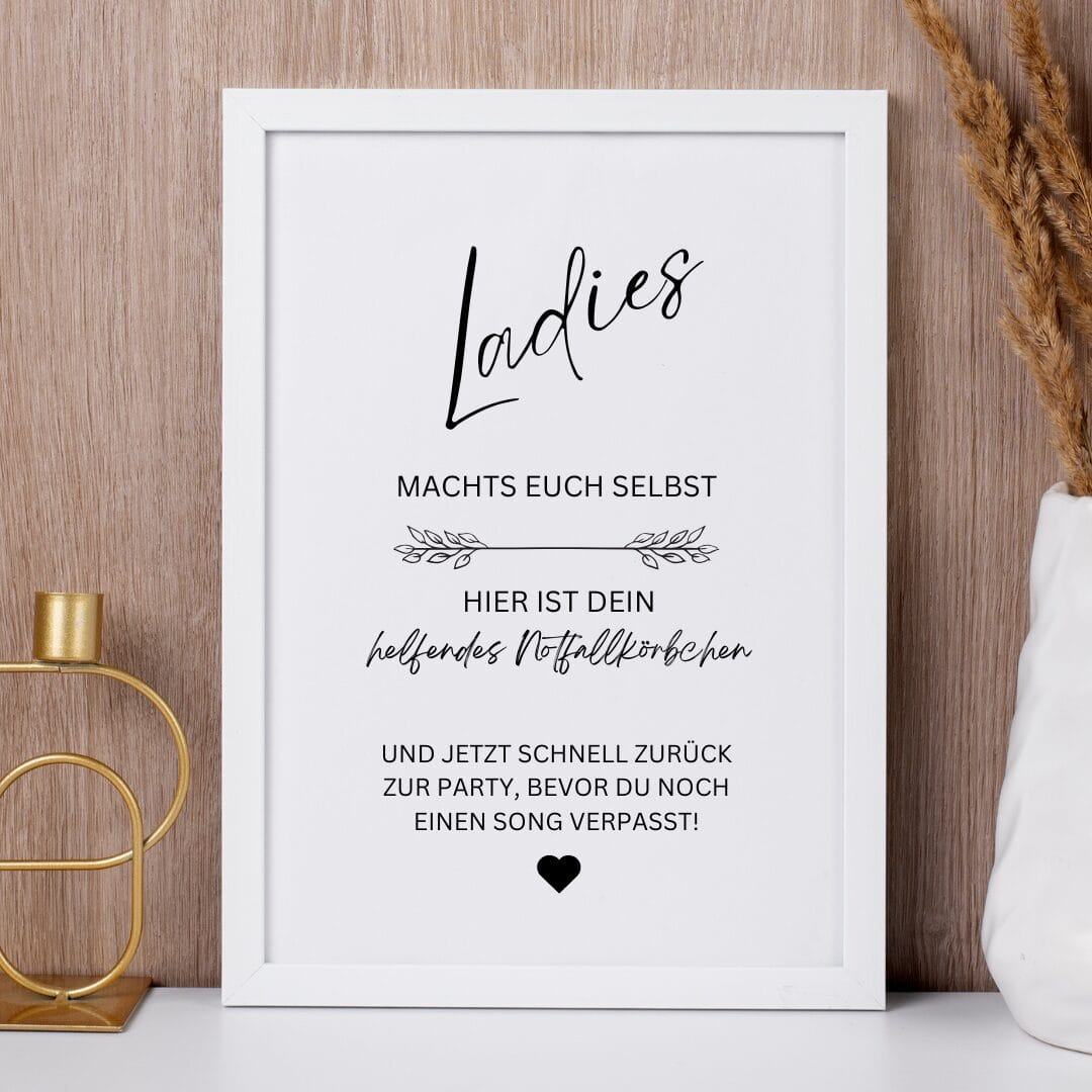 Auf einem Holzregal steht ein gerahmtes Schild in deutscher Sprache: "Meine Damen, macht's euch selbst. Hier ist dein helfendes Notfallkörbchen. Und jetzt schnell zurück zur Party, bevor du noch einen Song verpasst!".