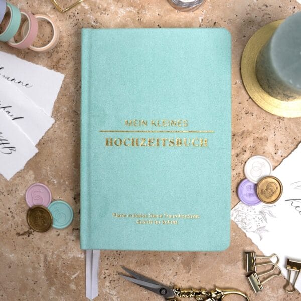 Mein kleines Hochzeitsbuch Hochzeitsplaner Wedding Planner Mint - Flatlay-Ansicht des Hochzeitsplaners auf einem braunen, dekorierten Tisch mit Accessoires, Wachssiegel, Hochzeitseinladung, Kerze