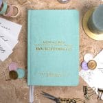 Mein kleines Hochzeitsbuch Hochzeitsplaner Wedding Planner Mint - Flatlay-Ansicht des Hochzeitsplaners auf einem braunen, dekorierten Tisch mit Accessoires, Wachssiegel, Hochzeitseinladung, Kerze