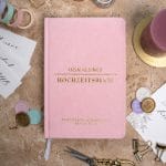 Mein kleines Hochzeitsbuch Hochzeitsplaner Wedding Planner Pink - Flatlay-Ansicht des Hochzeitsplaners auf einem braunen, dekorierten Tisch mit Accessoires, Wachssiegel, Hochzeitseinladung, Kerze