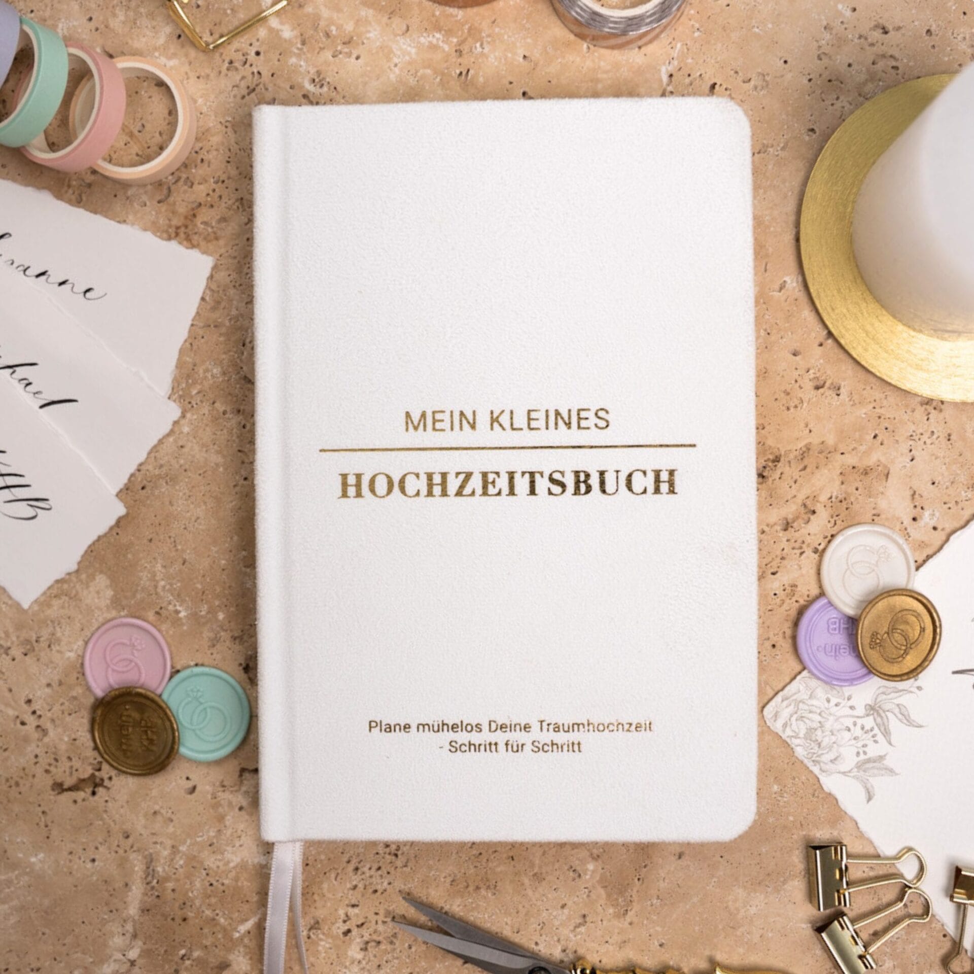 Mein kleines Hochzeitsbuch Hochzeitsplaner Wedding Planner Weiß - Flatlay-Ansicht des Hochzeitsplaners auf einem braunen, dekorierten Tisch mit Accessoires, Wachssiegel, Hochzeitseinladung, Kerze