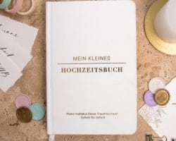Mein kleines Hochzeitsbuch Hochzeitsplaner Wedding Planner Weiß - Flatlay-Ansicht des Hochzeitsplaners auf einem braunen, dekorierten Tisch mit Accessoires, Wachssiegel, Hochzeitseinladung, Kerze