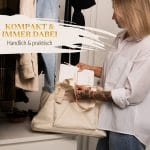 Mein kleines Hochzeitsbuch Hochzeitsplaner Wedding Planner Weiß - Kompakt und immer dabei - handlich und praktisch - Zukünftige Braut packt Hochzeitsplaner Wedding Planner in die Handtasche vor einer Garderobe