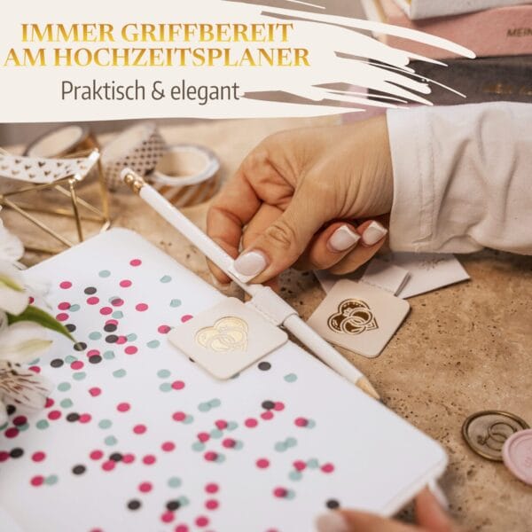 Stifthalter Stiftehalter Stiftschlaufe Pen Loop Hochzeitsplaner Weiß 5 Stifthalter Stiftehalter Stiftschlaufe Pen Loop Hochzeitsplaner Weiß - Immer griffbereit am Hochzeitsplaner - Praktisch und elegant. Hand schiebt Stift in Stiftschlaufe nach unten. Zukünftige Braut organisiert Wedding Planner mit Stiftschlaufe.